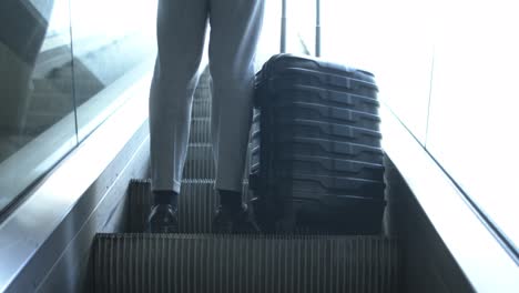 Low-angle-view-of-businessman-with-suitcase-on-escalator